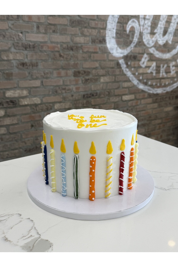 Buttercream birthday cake decorated with piped birthday candles and flames around the sides.