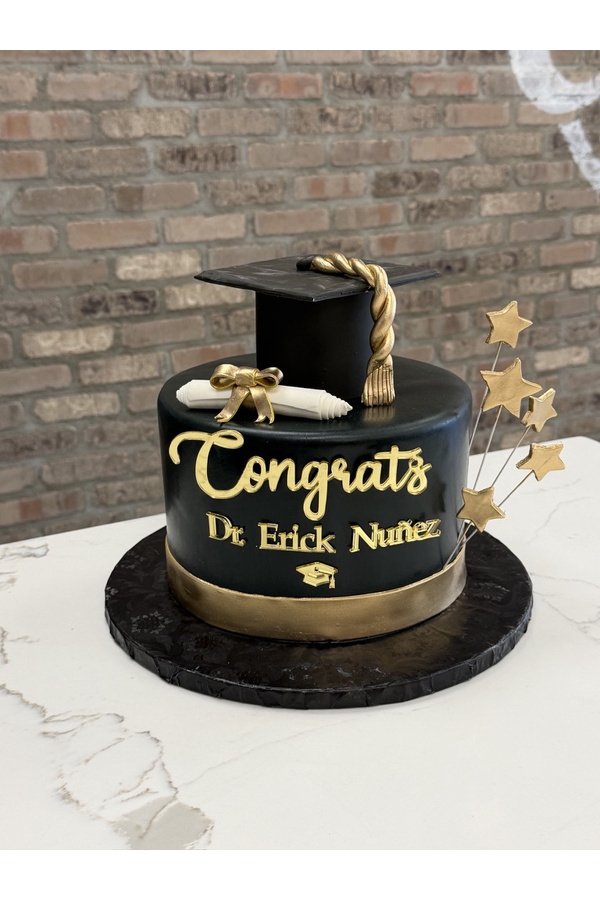 Black and gold graduation cake with graduation cap, diploma, tassel and stars.
