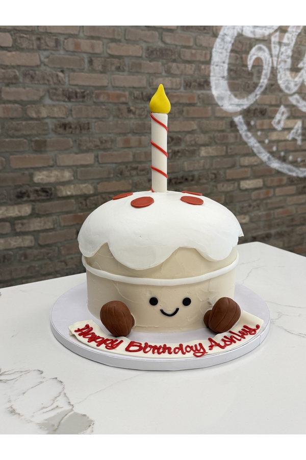 Cute sculpted birthday cupcake cake with smiling face, frosting, sprinkles, candle and little feet.