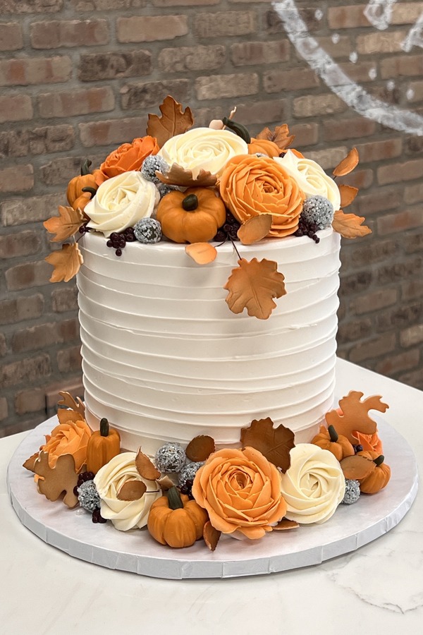 Fall cake with pumpkins, autumn leaves, textured buttercream and fancy buttercream flowers.