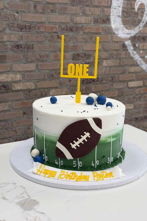 Football first birthday cake with football field, dimensional football and ONE goalpost topper.