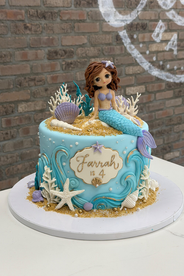 Mermaid birthday cake with sculpted mermaid, seashells, coral, starfish, ocean waves and sand details.