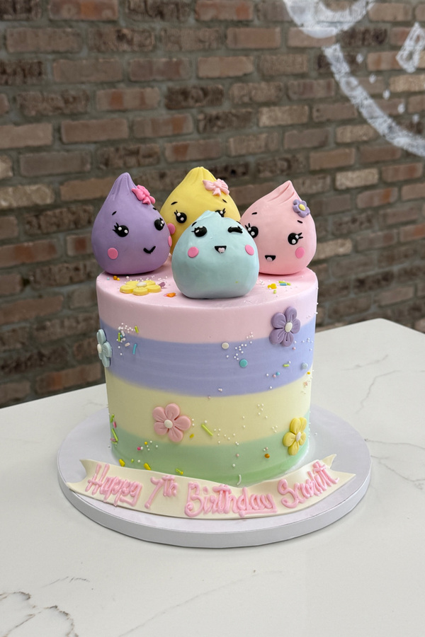 Squishy Dumplings 7th birthday cake with four character toppers, pastel details, flowers and sprinkles.