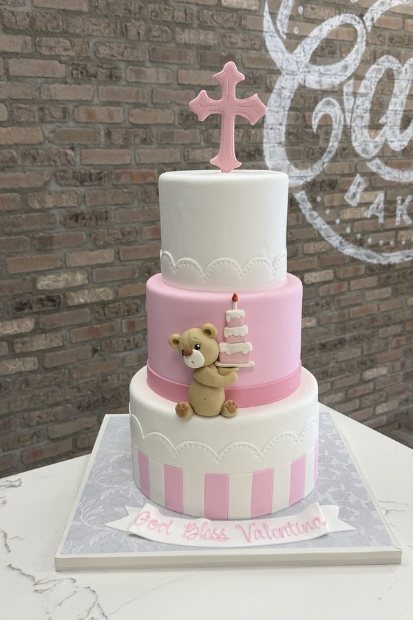 Three-tier Baptism cake with cross topper, teddy bear, miniature cake, stripes and scalloped details.