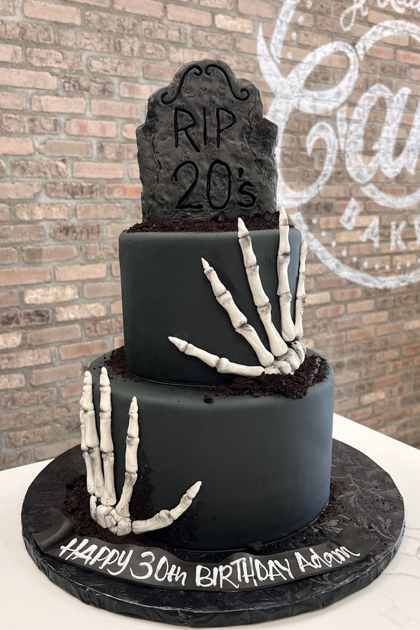 30th birthday cake with RIP 20s tombstone, sculpted skeleton hands and graveyard details.
