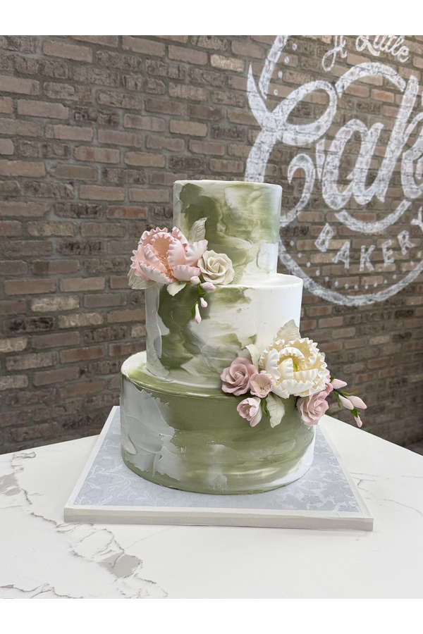 Three-tier sage green and white wedding cake with textured finish and sugar flowers.