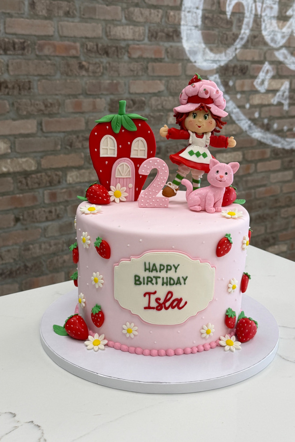 Strawberry Shortcake second birthday cake with character, strawberry house, number 2, strawberries and daisies.