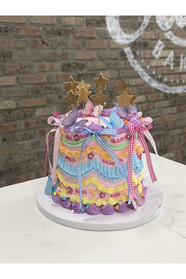 Vintage piped cake with colorful ruffles, butterflies, gingham bows and gold stars.